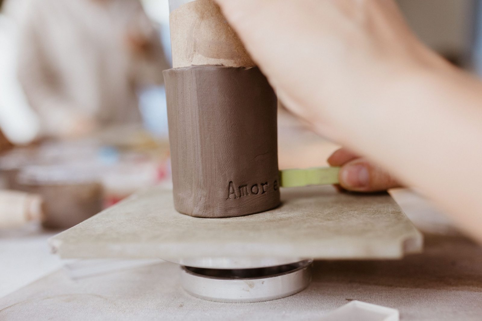 Close-up of hands crafting pottery indoors, showcasing artisanship and precision.