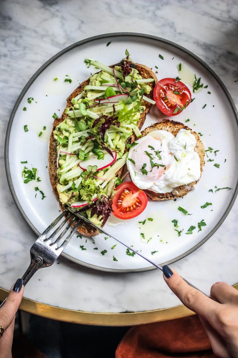 Vibrant breakfast plate featuring avocado toast with fresh vegetables and a poached egg.