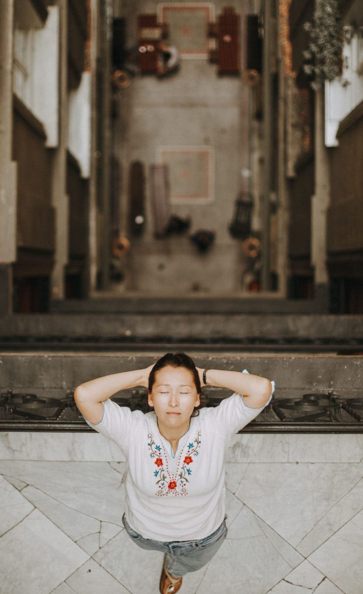 A woman with eyes closed leans on a balcony in Istanbul, capturing a moment of relaxation.